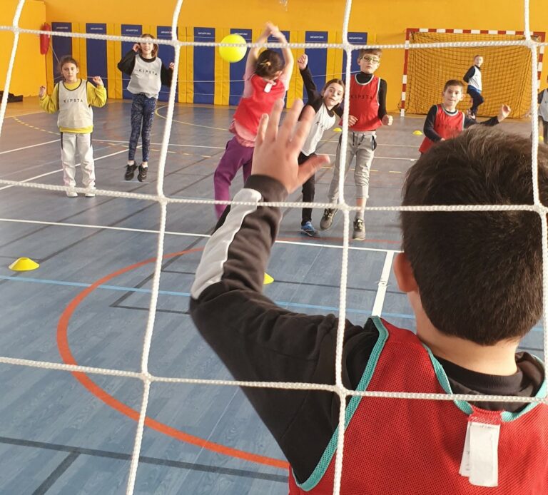 Enfants jouant au hand-ball dans un gymnase.