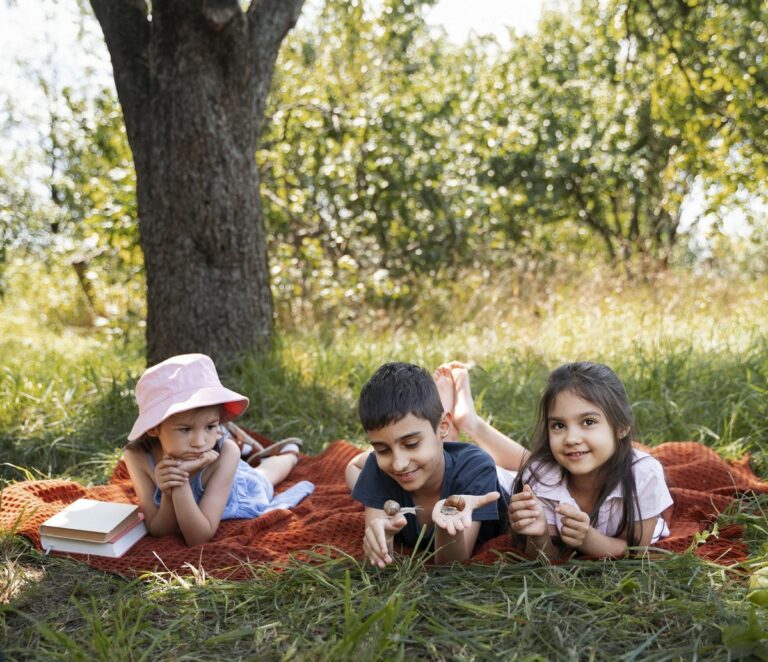 Des enfants étendus dans l'herbe au pied d'un arbre.