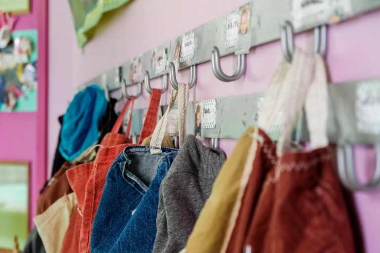 Des vêtements d'enfants suspendus à des porte-manteaux dans un couloir de la crèche Les écureuils.