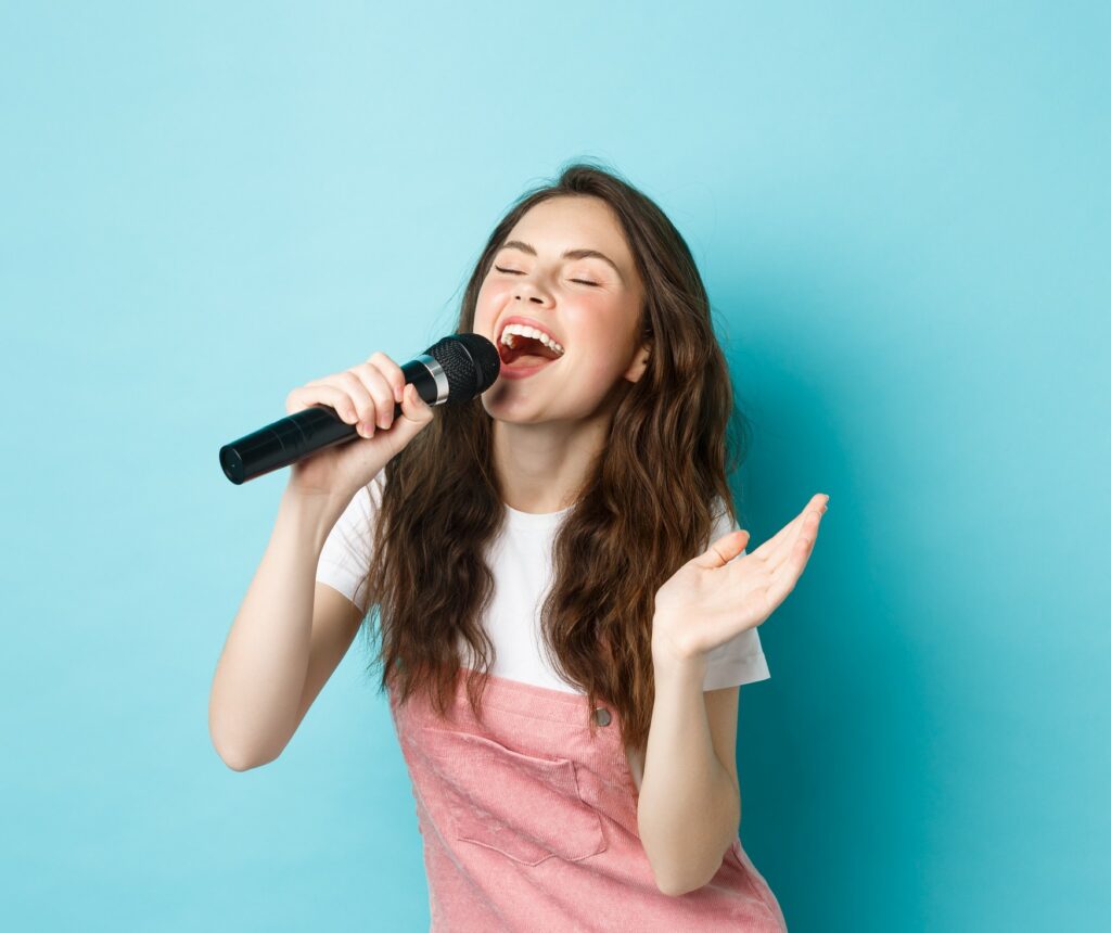 Une chanteuse avec un micro dans la main devant un fond bleu.
