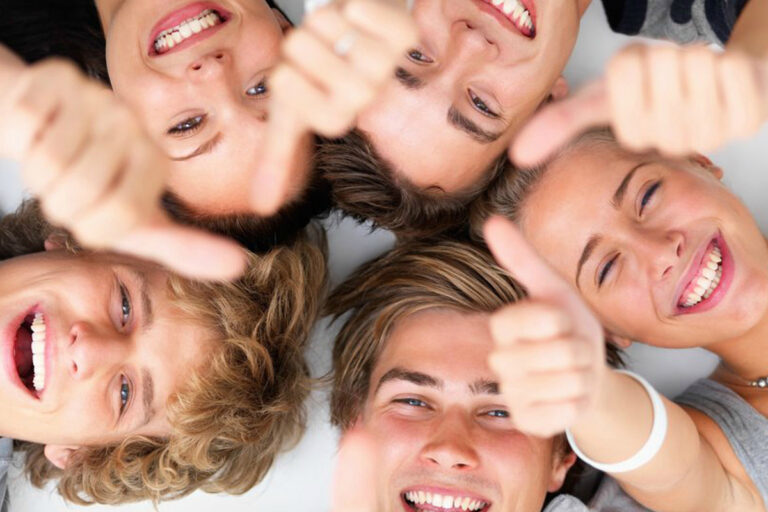 Des jeunes gens souriants te^te contre tête et tous avec le pouce levé.