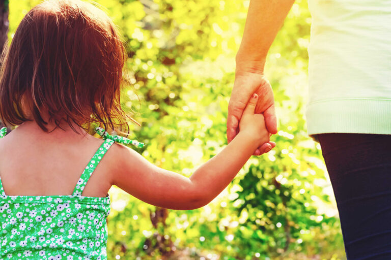 Une petite fille main dans la main avec son père lors d'une promenade.