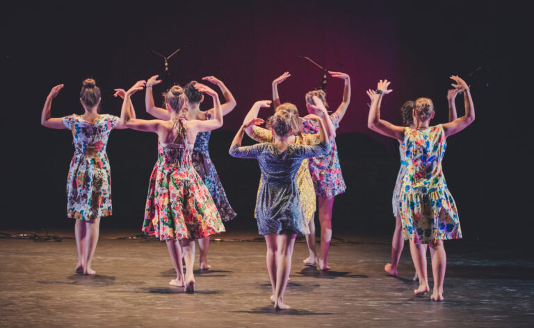 Un groupe d'adolescentes sont de dos dans un spectacle de danse contemporaine de l'école de danse Vaison Ventoux au théâtre antique de Vaison-la-Romaine.