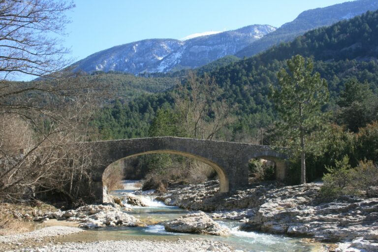Vue du Toulourenc passant sous le pont roman de Saint-Léger-du-Ventoux, avec le Mont Ventoux en arrière plan.