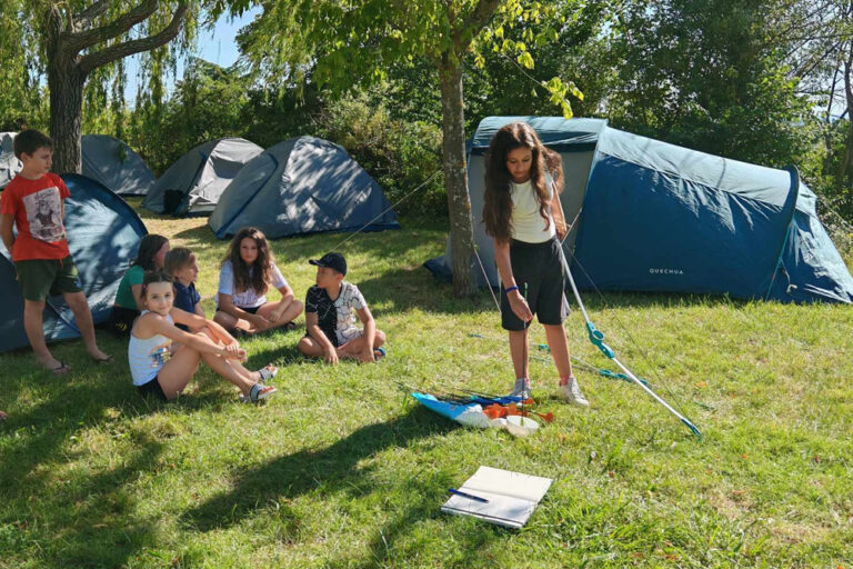 Des enfants assis devant leurs tentes de campings lors d'in bivouac passerelle avec le Club Jeunes.