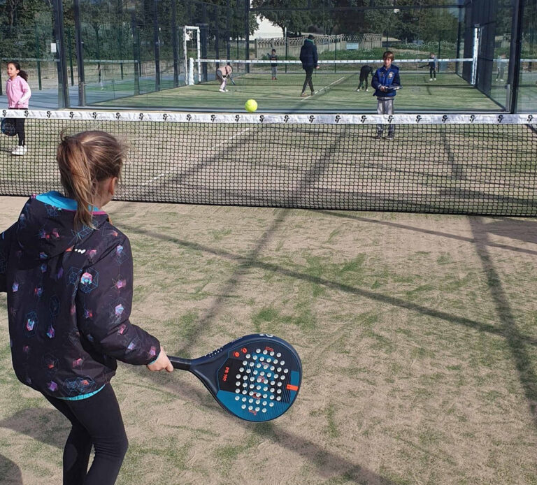 Fillette de dos jouant avec une raquette de padel tennis.