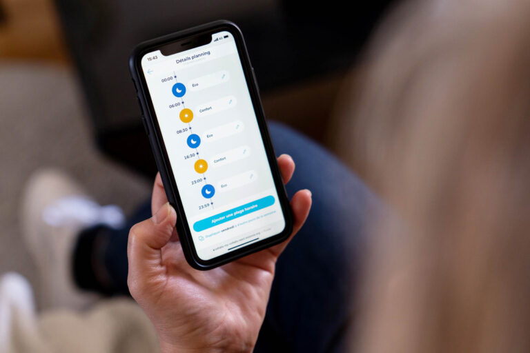 Un smartphone tenu dans une main qui affiche l'application de la la société Voltalis.