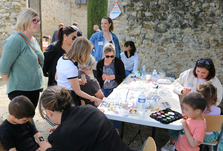Des personnes assises ou debout autour d'une table participent à un atelier de maquillages.