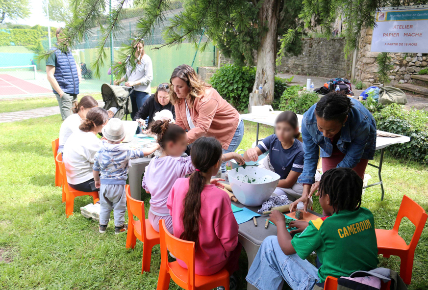 En extérieur, des adultes et des enfants participent à un atelier créatif.