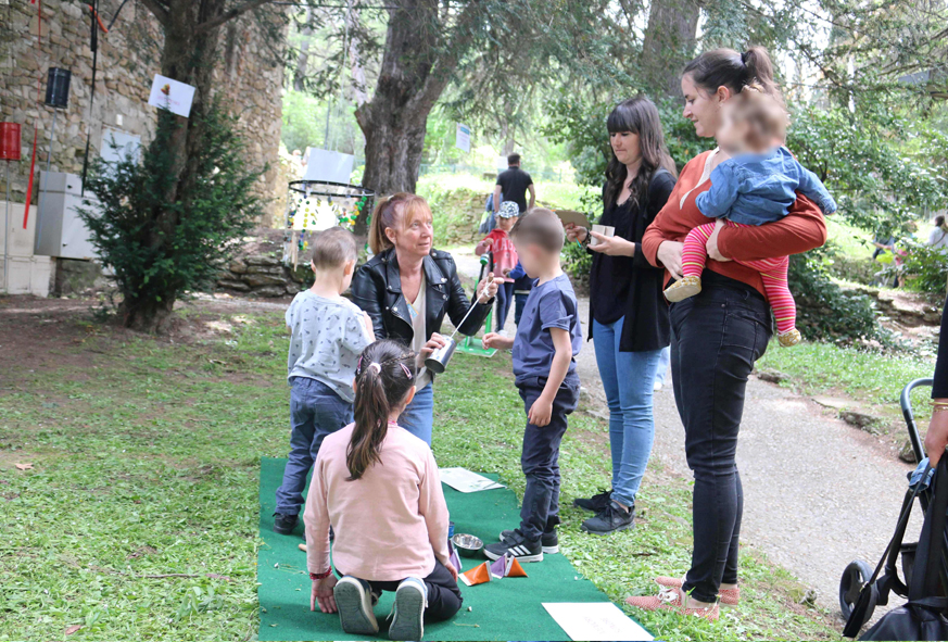 En extérieur, des enfants et des parents découvrent des instruments de musique fabriqués avec des matériaux de récupération lors d'un atelier de la Journée festive en famille.