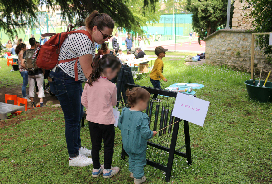 Une maman et deux enfants jouent avec un xylophone bricolé avec des éléments de récupération.
