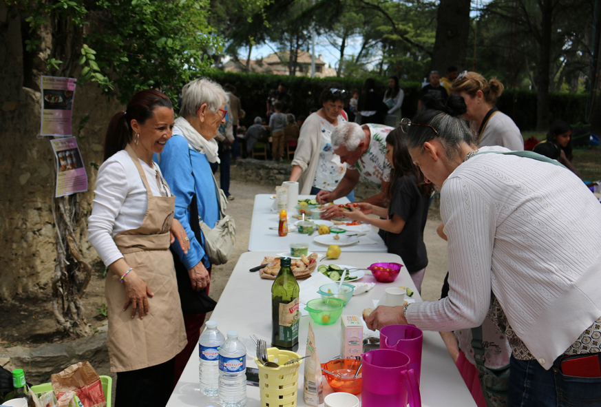 Des personnes sont debout autour d'une table sur laquelle sont posés des ustensiles de cuisine et des fruits et légumes pour participer à un atelier culinaire.