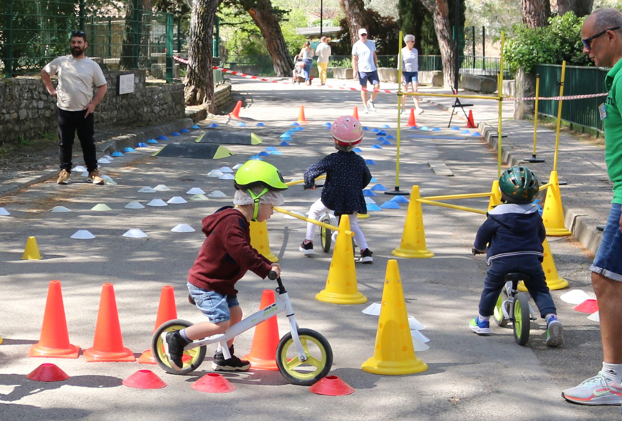 De jeunes enfants pratiquent un parcours avec des draisiennes à la Journée festive en famille 2025.