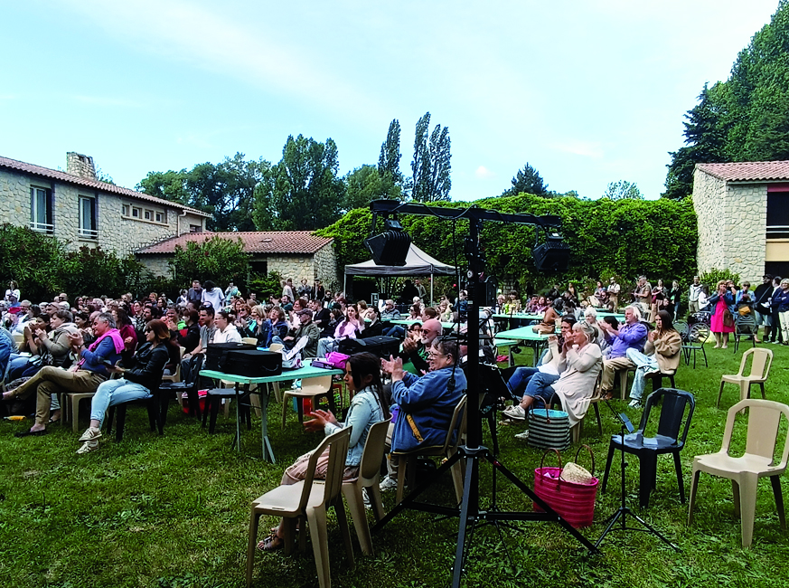 Un public nombreux assis dans un grand jardin assiste au concert champêtre de l'école intercommunale de musique Vaison Ventoux.