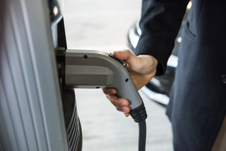 Close-up of man charging car at electric vehicle charging station