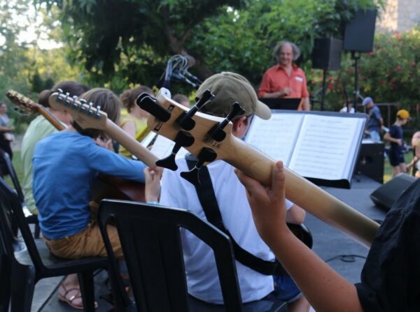 Des guitaristes de l’école de musique photographiés de dos lors d'un concert.