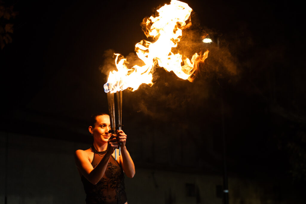 Jeune femme portant des baguettes enflammées pour un spectacle nocturne sur le thème du feu.