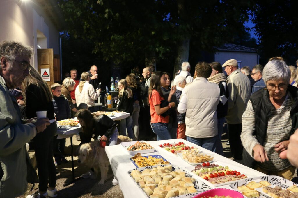 De nombreuses personnes sont debout autour d'un buffet, de nuit.