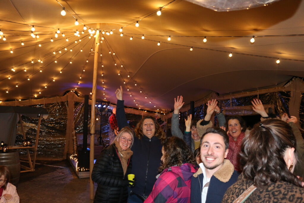 Quelques personnes sourient et font la fête sous un chapiteau.