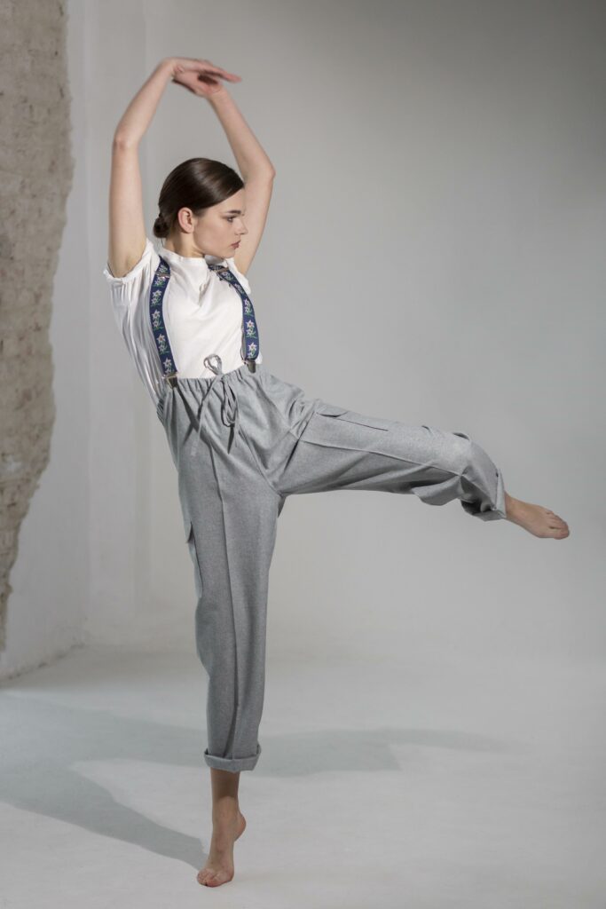 Une danseuse de modern jazz prend la pose appuyée sur un seul pied et les bras en l'air.