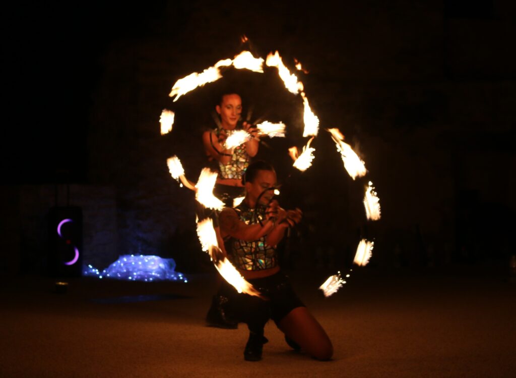 Deux femmes font des jeux de lumière de nuit avec des baguettes enflammées.