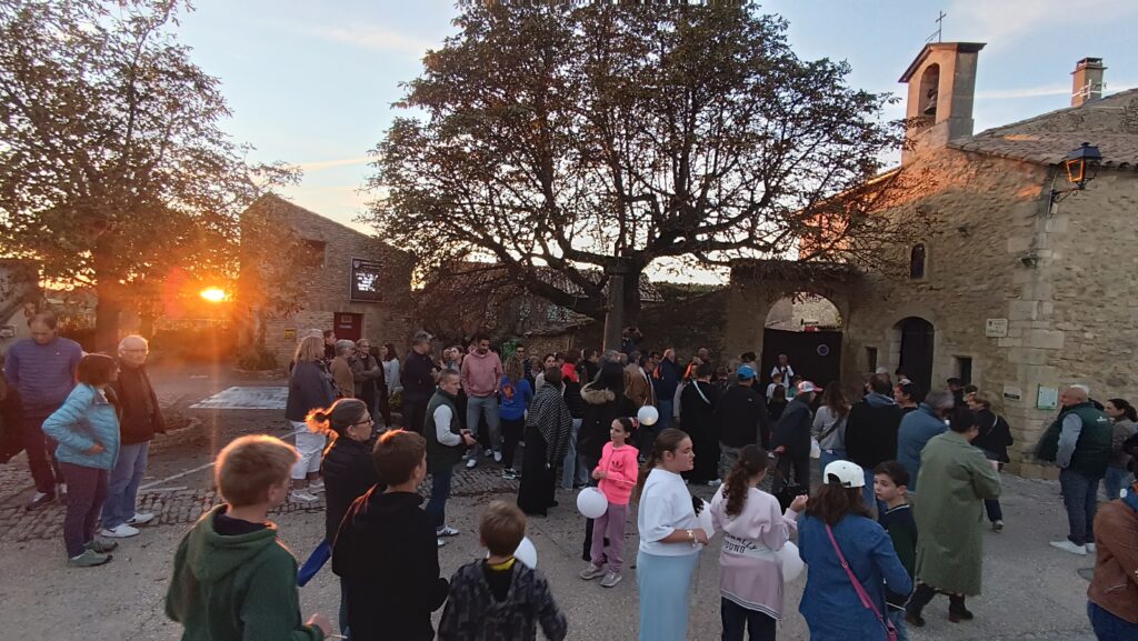 Le public des Automnales, réuni au coucher du soleil sur la place de la mairie de Faucon pour une lecture de contes.