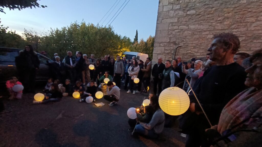 Une foule de personnes sont dans le village de Faucon de nuit, avec des lampions.